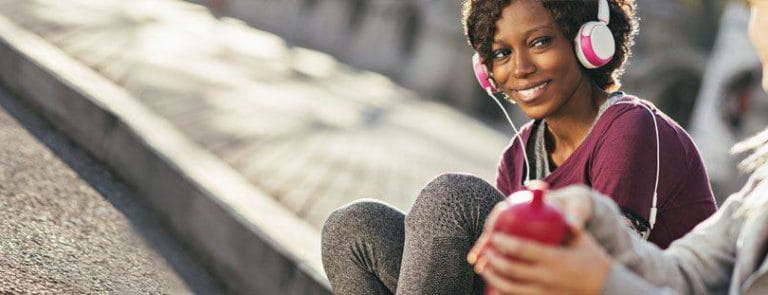 A Women Sat On A Pavement Listening to Music on Headphones