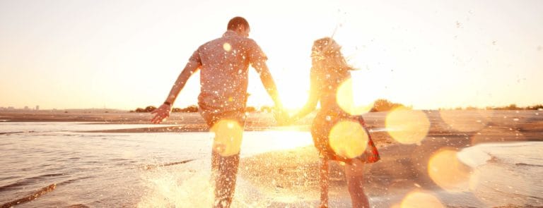 couple splashing in the waves at sunset on a beach