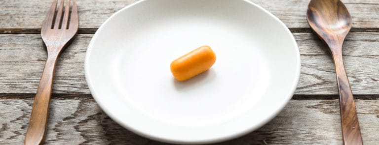 A plate with a baby carrot on it and cutlery