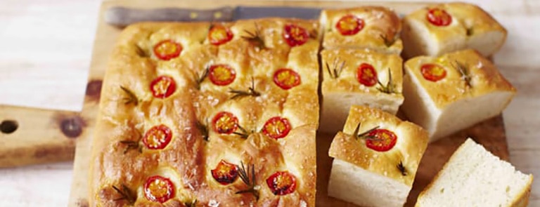 Rosemary and tomato focaccia on a wooden chopping board