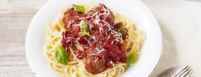 A bowl of spaghetti with meatballs and sauce