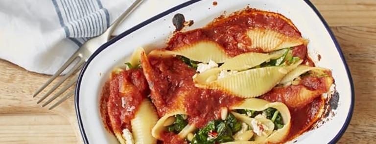 Baked spinach and tomato pasta shells in a tray