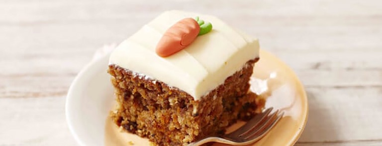 A slice of dairy free carrot cake with icing decoration
