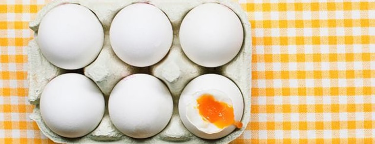 half a dozen eggs with one cracked and the yolk showing