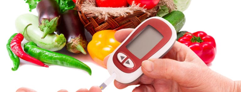 A Blood Glucose Meter for diabetes in front of different fruit and vegetables