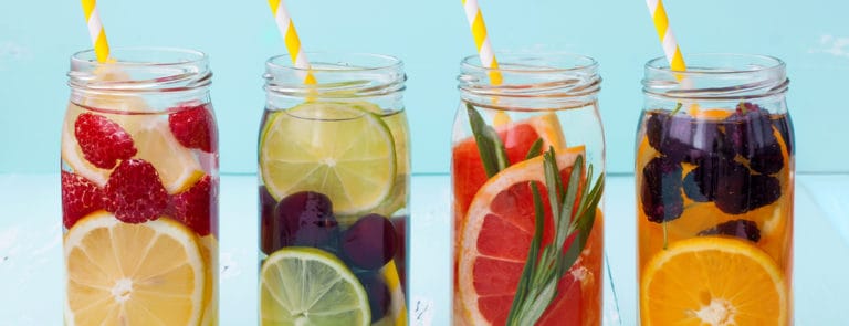 Jars cotaining different fruits and water with straws sticking out