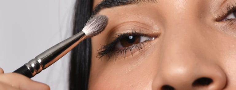 A women applying make up to just above her eye
