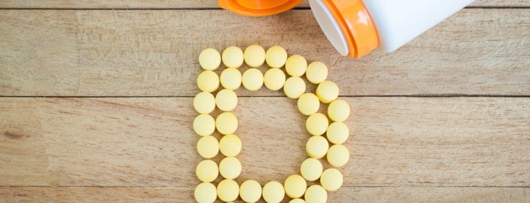 Vitamin D pills forming a D shape on a wooden background