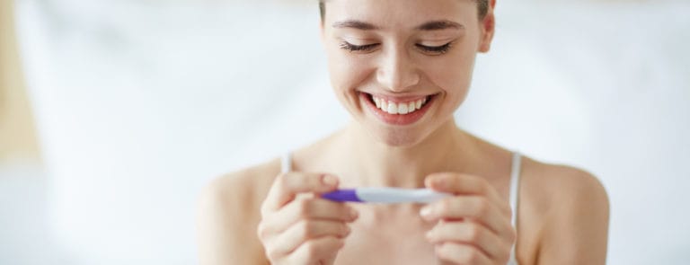 woman looking at pregnance test in happiness