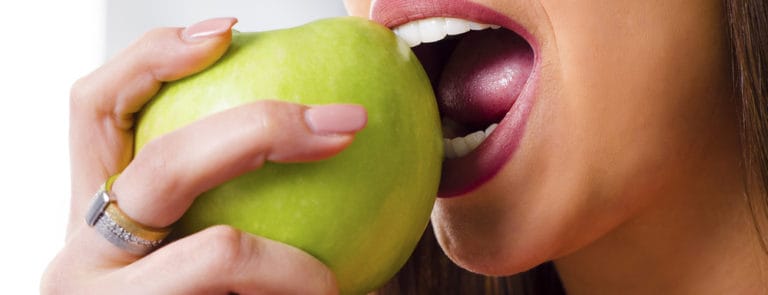 woman with perfect teeth biting green apple