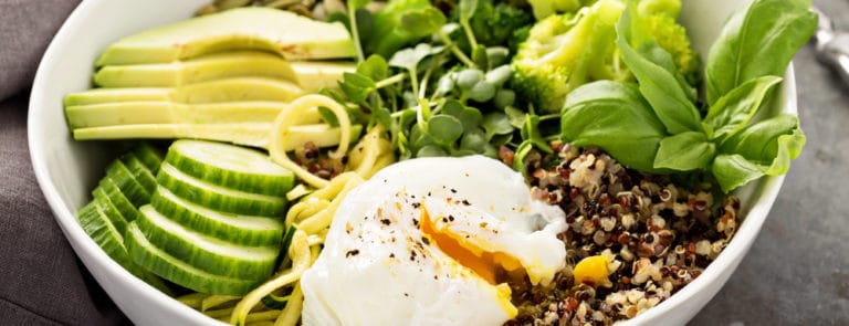 Green and healthy vegetarian grain bowl with quinoa, avocado, cucumber and poached egg
