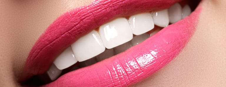 woman's smile with healthy white teeth, bright pink lipstick