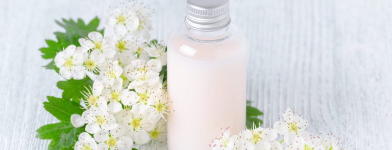 Bottle of organic shower gel with fresh flowers