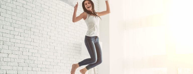 woman jumping on her bed full of energy