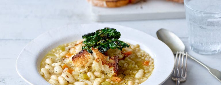 Pearl Barley Ribollita served in a white bowl topped with Crispy Cavolo Nero