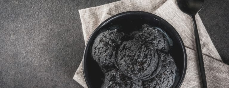 Bowl of black, liquorice ice cream against a black background