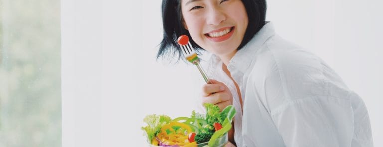 Asian young beautiful woman eating salad with happy mood smile on white background