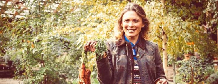 A woman holding freshly picked carrots in an allotment. Carrots are a rich source of vitamin A