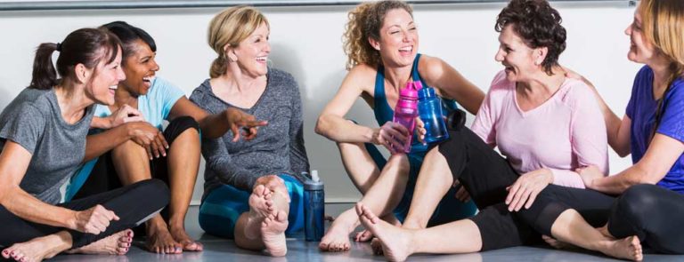 A group of women sitting down on the floor of a fitness studio in sports clothing