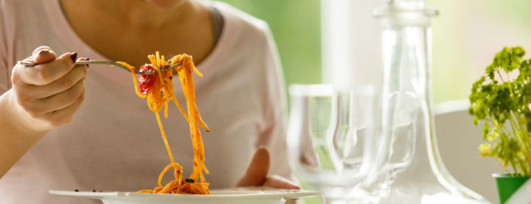 Woman eating a tomato pasta