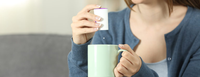 woman adding a sweetner to her hot drink