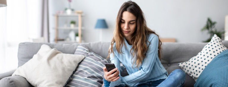 A woman at home on her own using her mobile to reconnect with an old friend to cure loneliness