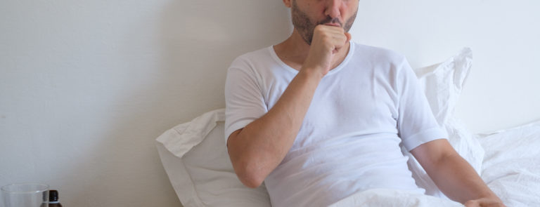 man coughing in bed