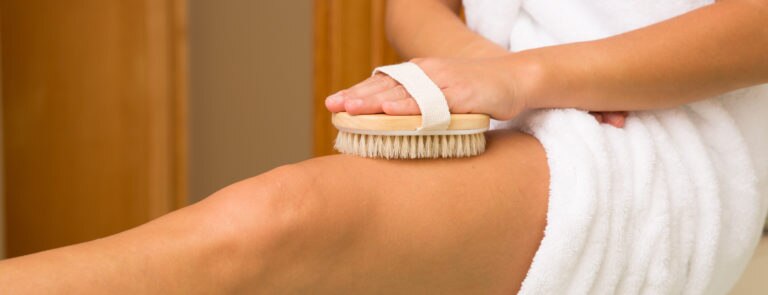 woman using body brush to get rid of cellulite