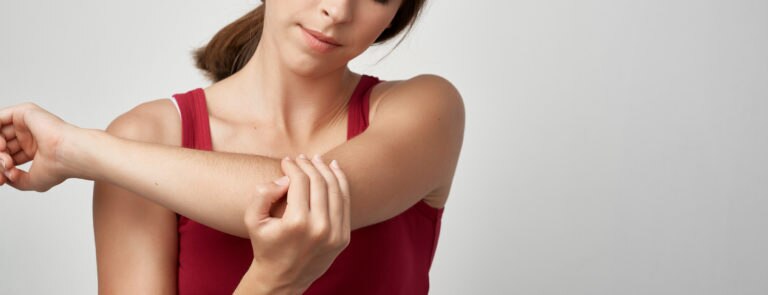 A lady looking and touching her elbow which appears to be painful.