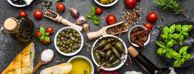 A spread of olives, bread, oils and an array of vegetables on a table.