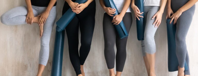 group of women with excersize mats going to yoga vs pilates