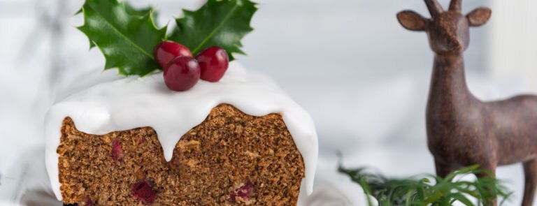 A vegan Christmas pudding topped with holly and berries. With a stag statue behind.
