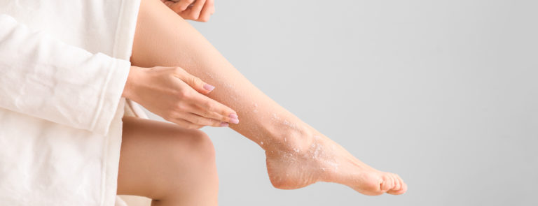 A lady rubbing an exfoliating cream into her legs.