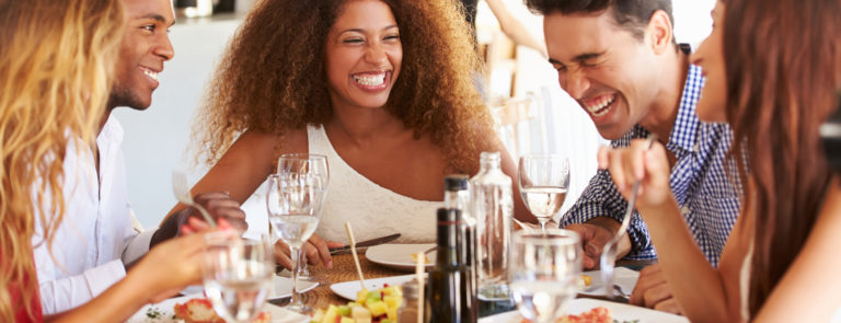 group of friends laughing at dinner table