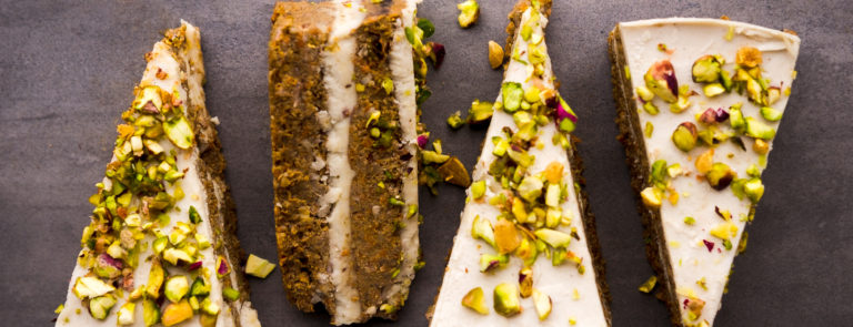4 Vegan carrot cake slices topped with pistachios.