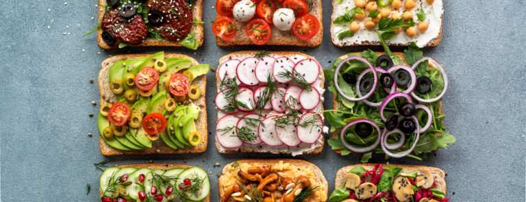 An array of 9 breads with various vegan fillings such as avocado and tomato.