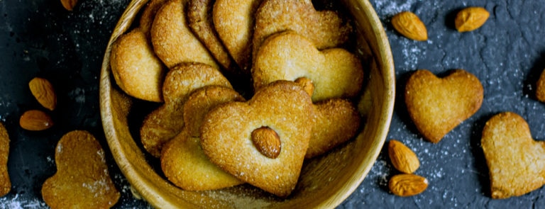 Almond, biscuits in a heart shape, in a bowl, with almonds in the centre.