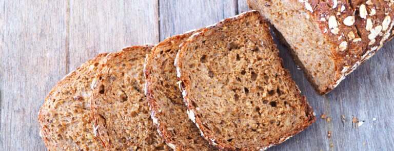 A wholemeal bread loaf, with slices scattered in front.