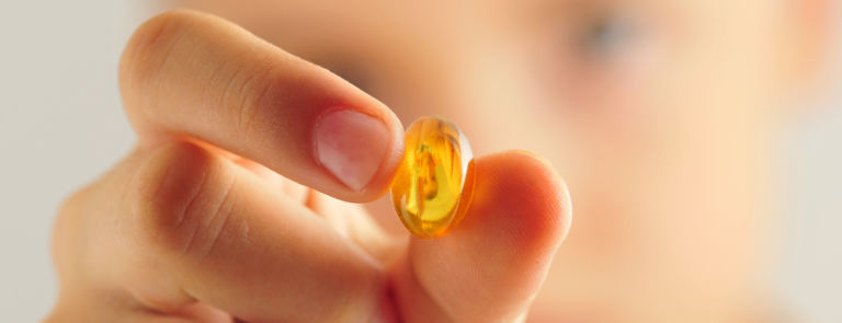 a young boy holding an omega 3 capsule
