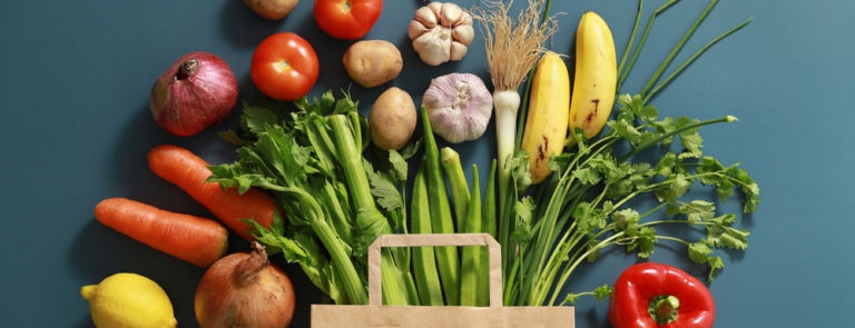 assortment of vegetables next to a paper grocery bag