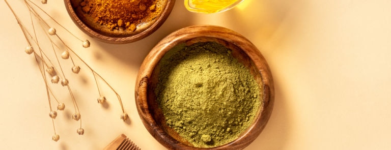 henna powder in a wooden bowl next to a wooden comb