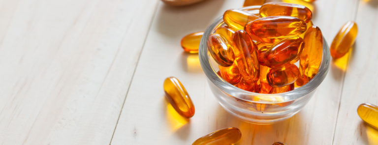 A table filled with omega 3 capsules in a bowl, on a spoon and scattered around.