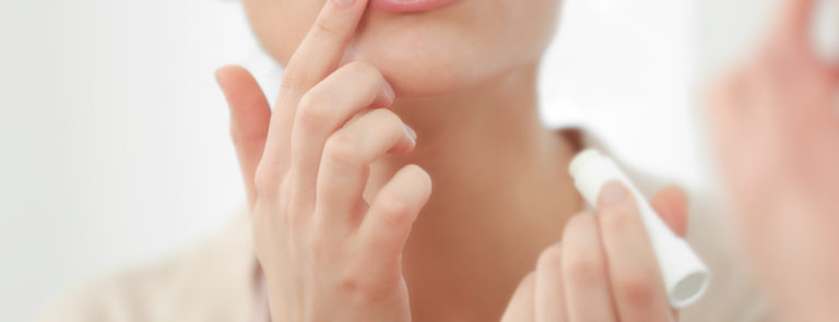 A lady applying lip balm to her lips.